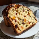Two slices of homemade Panettone bread filled with raisins and candied fruit, presented on a white plate.