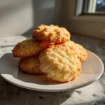 A stack of golden brown shortbread cookies on a white plate, bathed in sunlight.