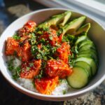 Close-up of a vibrant salmon bowls featuring glazed salmon cubes over rice, avocado slices, and cucumber.
