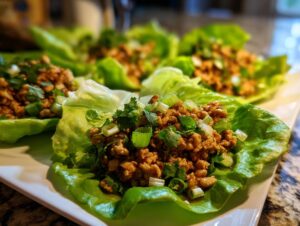 Close-up of fresh thai chicken lettuce wraps filled with savory ground chicken and topped with green onions and cilantro.