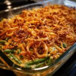 Close-up of a freshly baked vegan green bean casserole topped with golden crispy fried onions.
