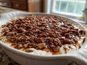 A white baking dish filled with creamy pecan pie dip topped generously with glazed pecans.