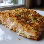 A close-up of a perfectly cooked piece of stuffed salmon showing the creamy filling and golden, crispy breadcrumb topping.
