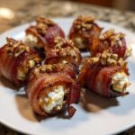Close-up of six bacon wrapped stuffed dates, filled with cheese and topped with chopped pecans.