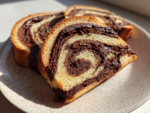Three slices of rich, chocolate swirl pinwheel cookies showing the beautiful spiral pattern on a speckled plate.