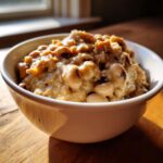 A creamy, savory bowl filled with cooked black eyed peas and thick sauce, sitting on a wooden table.