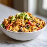 Close-up of creamy southwest chicken salad featuring avocado, black beans, corn, and tomatoes in a white bowl.