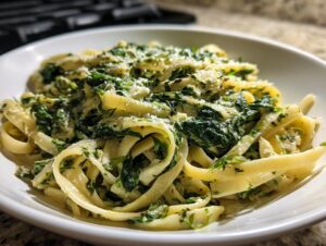 Close-up of creamy spinach pasta tossed with fettuccine noodles and topped with grated Parmesan cheese.
