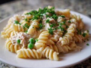Close-up of creamy tuna pasta made with fusilli noodles, peas, and topped with fresh parsley.