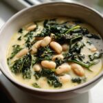Close-up of a bowl of creamy tuscan white bean soup featuring cannellini beans and dark green kale.