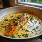 A golden-brown dijon chicken breast simmering in a rich, creamy sauce, garnished with fresh parsley.