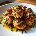 Close-up of golden brown garlic butter chicken bites coated in sauce and sprinkled with fresh parsley.