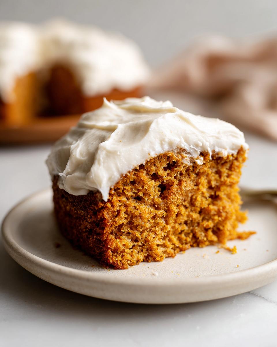 Close-up of a moist slice of applesauce cake topped with thick, white cream cheese frosting.