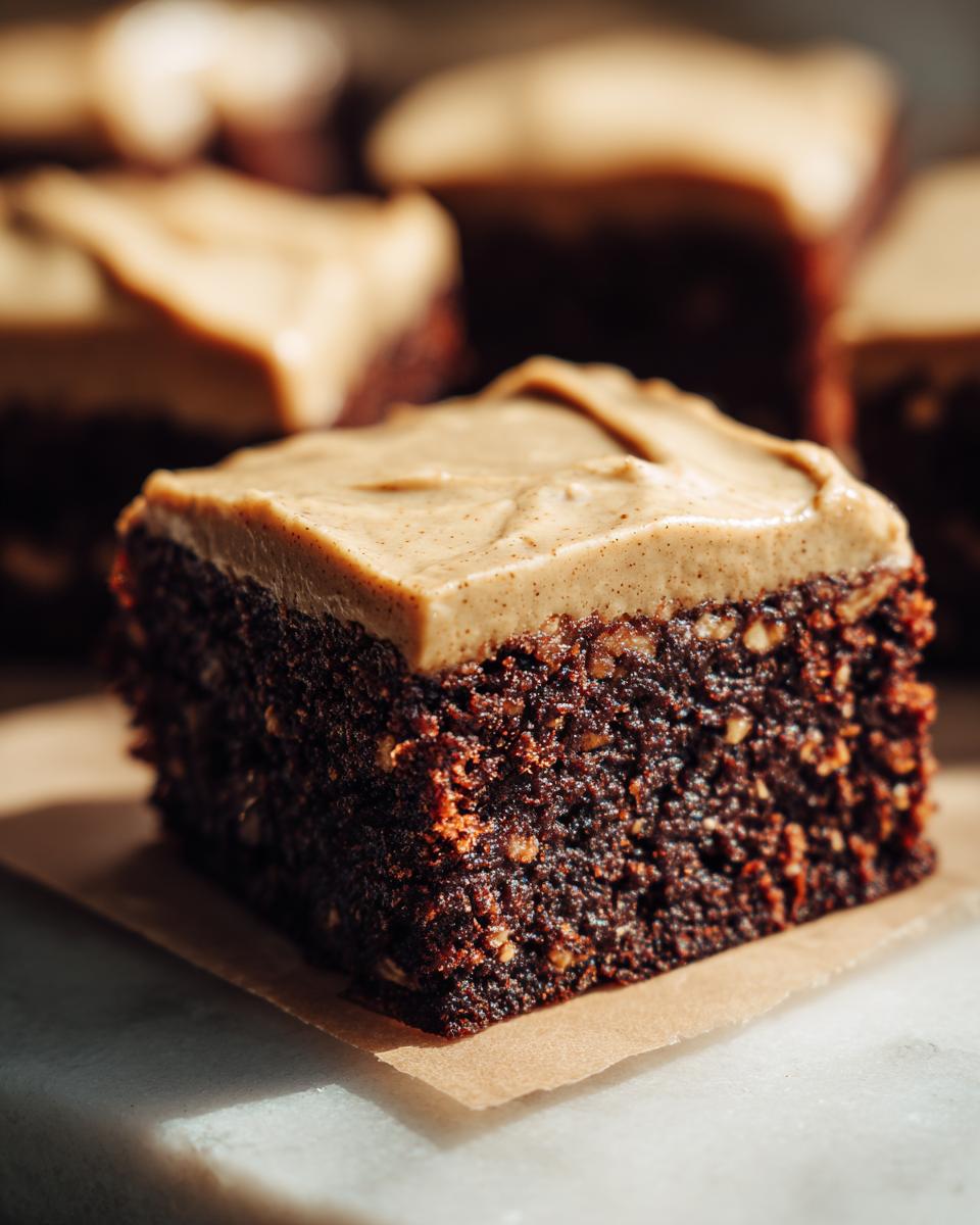 Close-up of a thick, moist square of banana bread brownies topped with light brown frosting.