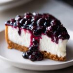 A close-up of a creamy slice of no-bake blueberry cheesecake topped with rich blueberry compote.