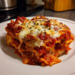 A close-up shot of a generous serving of lazy lasagna topped with melted mozzarella and herbs on a white plate.