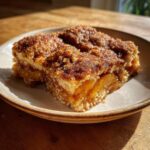 Two squares of warm snickerdoodle cobbler topped with a thick, sugary cinnamon crust, served on a plate.