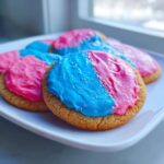 Close-up of sugar cookies topped with vibrant pink and blue sugar cookie icing that hardens, featuring silver sprinkles.