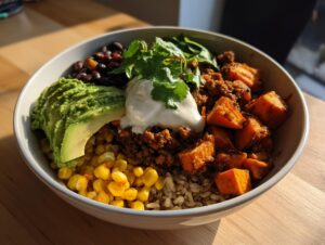A vibrant sweet potato taco bowl featuring seasoned sweet potatoes, black beans, corn, avocado, and sour cream.
