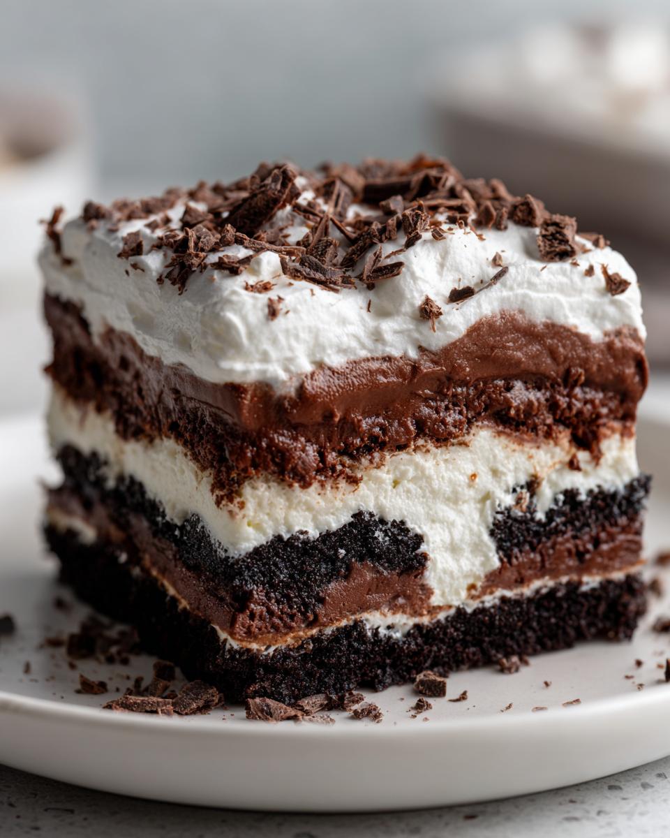 Close-up of a layered brownie refrigerator cake slice showing dark cake, white cream, chocolate mousse, and whipped topping.