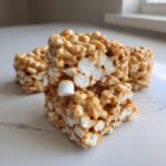 Close-up stack of gooey avalanche cookies squares showing crispy cereal, peanut butter coating, and marshmallows.