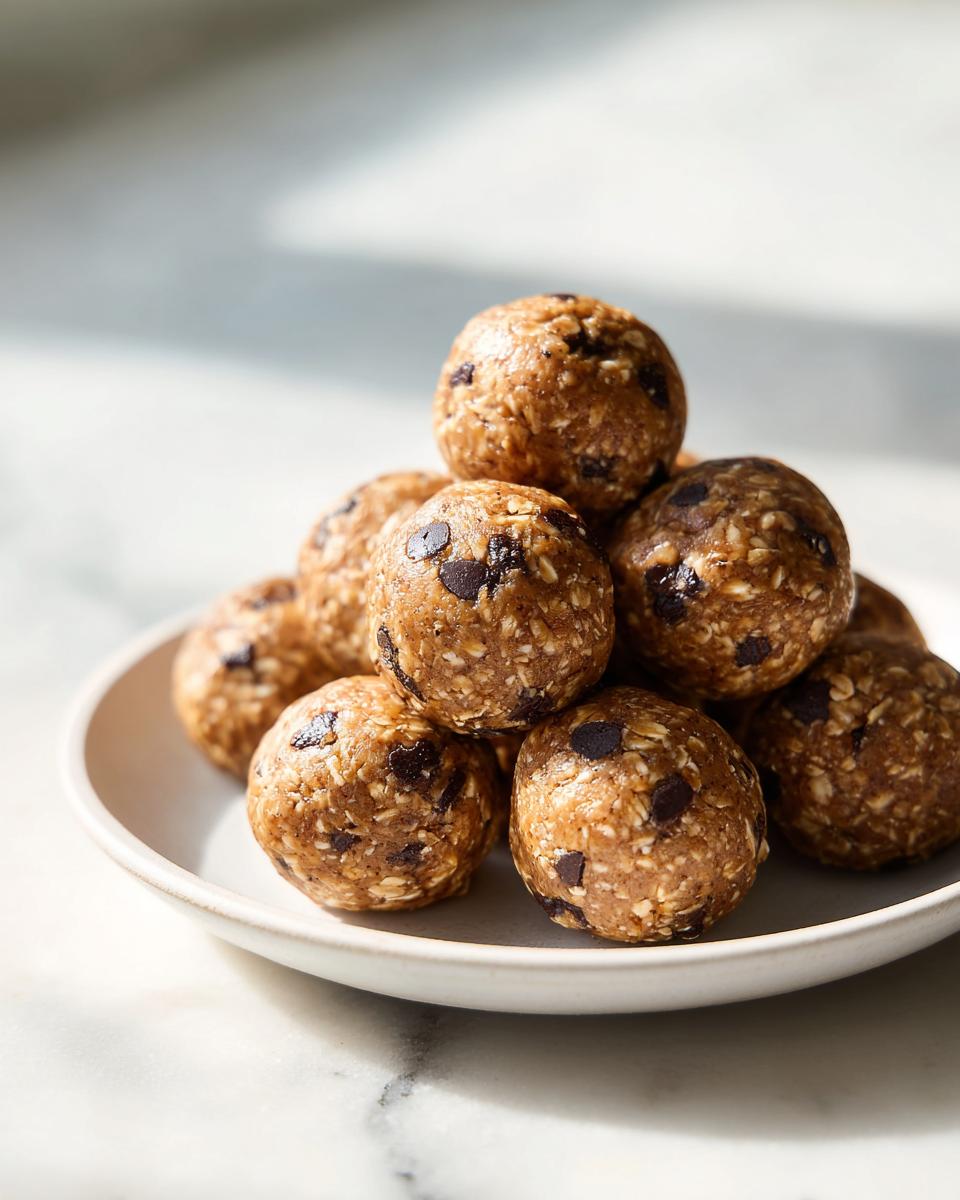 A stack of homemade chocolate chip protein balls piled high on a small white plate.