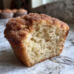 Close-up of a cinnamon sugar french toast muffins cut in half, showing its fluffy texture and sugary topping.