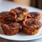 A stack of freshly baked french toast muffins topped with a thick layer of cinnamon sugar.