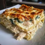 A close-up of a rich, layered slice of creamy chicken lasagna with a browned, cheesy top.