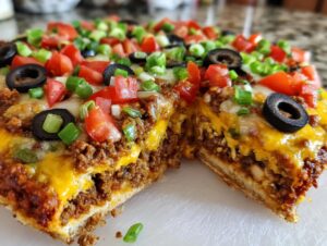 A thick slice of 10-layer Mexican pizza showing layers of seasoned beef, cheese, tomatoes, olives, and green onions.