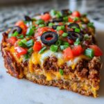 A thick, layered slice of Mexican pizza showing seasoned beef, melted cheese, tomatoes, olives, and green onions.