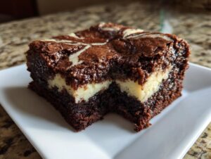 A close-up of a rich, fudgy cream cheese brownies square with a visible cream cheese layer and chocolate swirl top.