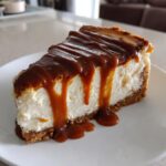 A decadent slice of creamy salted caramel cheesecake topped with thick, dripping caramel sauce.
