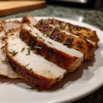 Close-up of moist, sliced slow cooker turkey breast seasoned heavily with rosemary and spices.