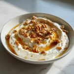 A bowl of creamy whipped ricotta dip topped with hot honey drizzle and chopped walnuts.