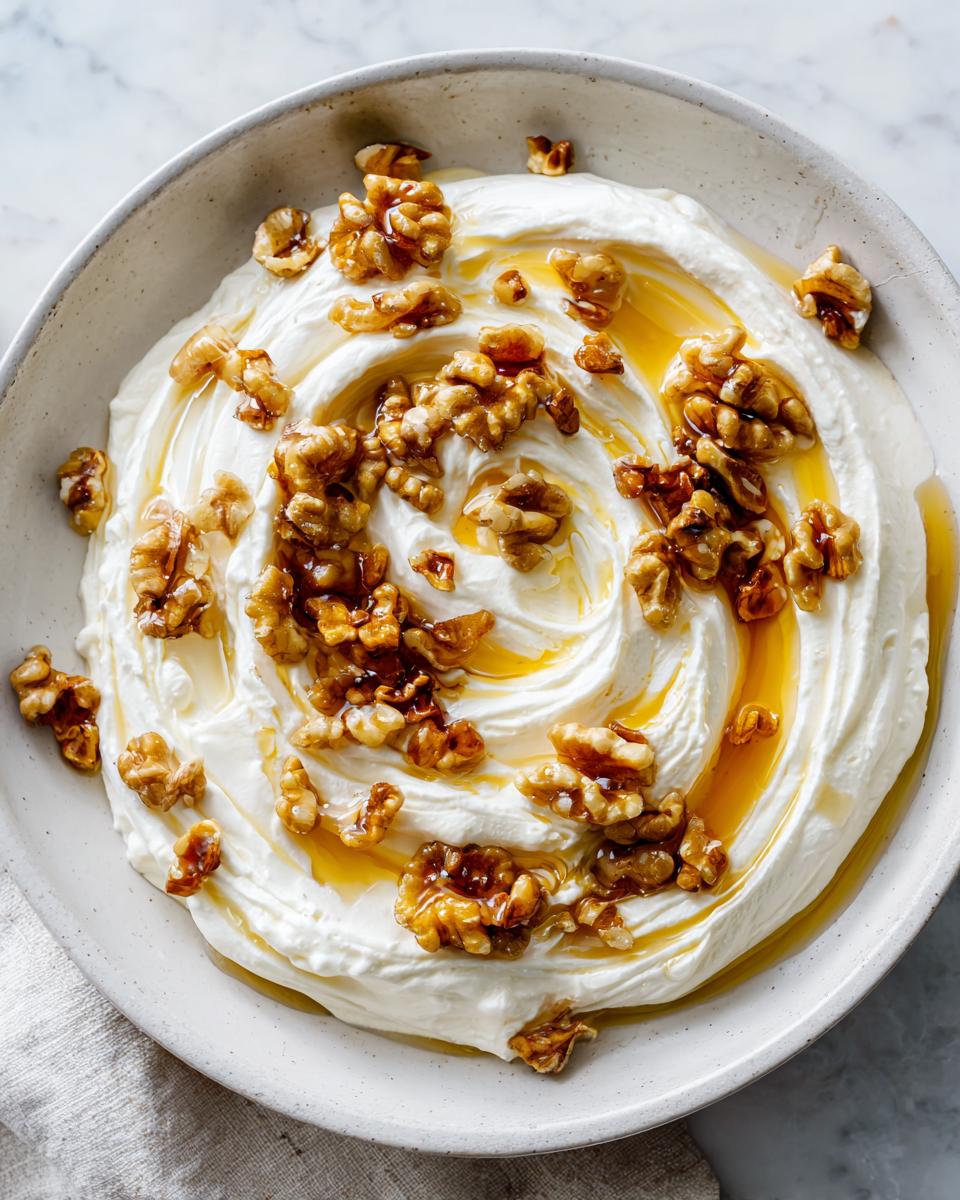 A bowl of creamy whipped ricotta dip swirled and topped generously with walnuts and a drizzle of honey.