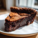 Close-up of a rich, dark slice of fudge pie showing a dense, gooey interior and a slightly cracked top.