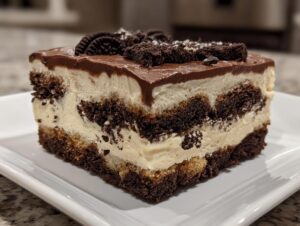 A decadent slice of Baileys Chocolate Cheesecake Trifle showing layers of cream, chocolate cake crumbs, and topped with chocolate ganache and cookies.