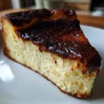 A close-up of a creamy slice of Basque cheesecake featuring its signature dark, caramelized top.