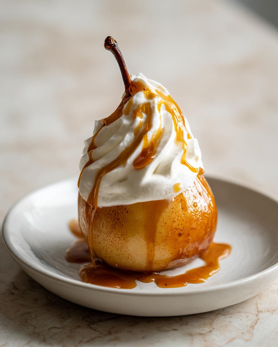 A beautifully presented poached pears dessert topped with whipped cream and caramel sauce on a white plate.