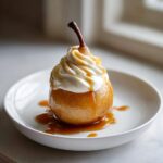 A beautifully presented poached pears dessert topped with whipped cream and drizzled with caramel sauce.