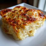 A close-up of a perfectly baked slice of cheesy scalloped potatoes with a golden-brown, herbed crust.