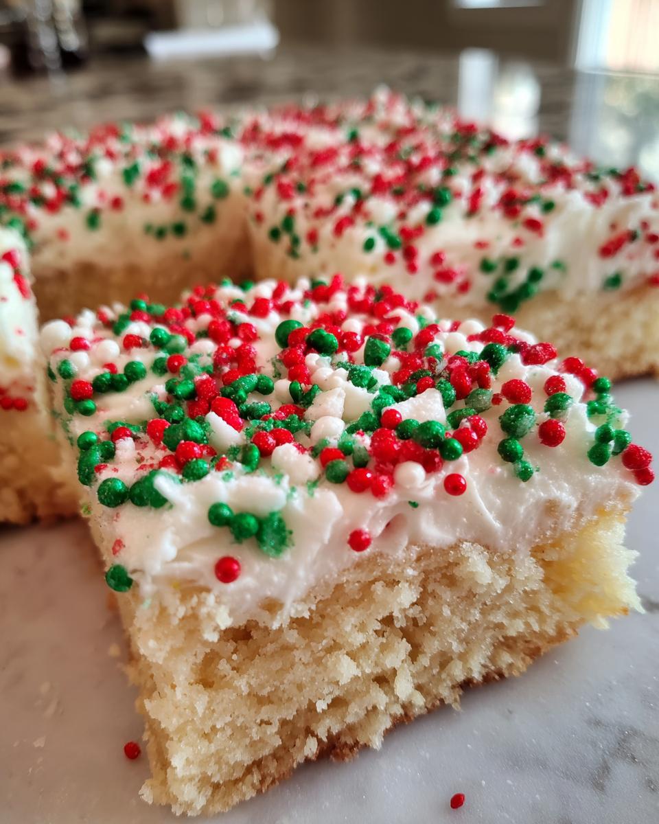 A close-up of a square slice of soft Christmas sugar cookie bars topped with white frosting and red, green, and white holiday sprinkles.
