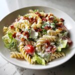 Close-up of creamy blt pasta salad featuring rotini pasta, crisp lettuce, cherry tomatoes, and crumbled bacon.