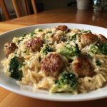 Close-up of a creamy bowl of chicken sausage and broccoli orzo, topped with grated Parmesan cheese.
