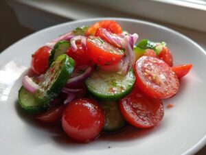 Close-up of a vibrant cucumber tomato salad featuring sliced cherry tomatoes, cucumbers, and red onion.