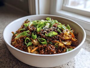 A close-up of a white bowl filled with savory egg roll in a bowl, topped with green onions and sesame seeds.
