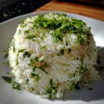 A mound of fluffy cilantro lime rice, perfectly molded and topped generously with chopped fresh cilantro and lime zest.