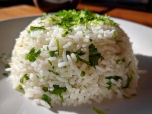Close-up of a perfectly molded mound of fluffy cilantro lime rice, topped with fresh cilantro and lime zest.