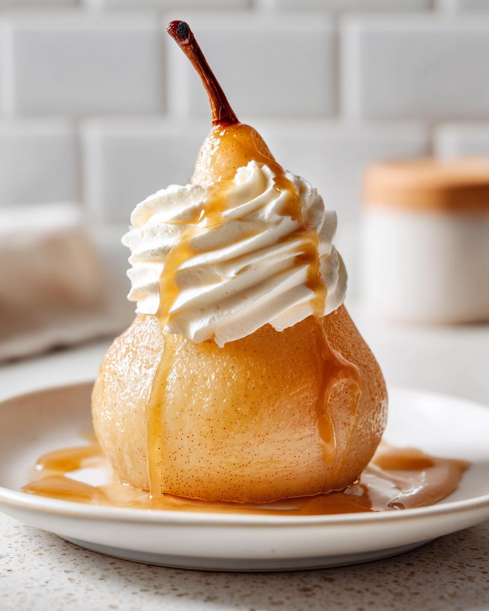 A single, glistening poached pear topped with a swirl of whipped cream and drizzled with caramel sauce.